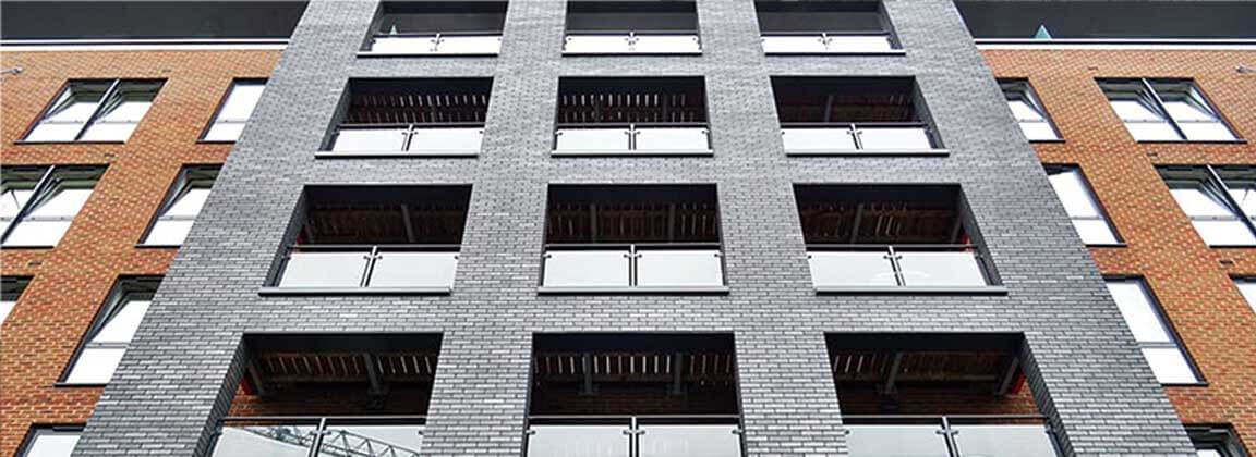 The exterior wall of the building is calm and steady with ADD STONE WA - Multicolor Faux-Stone Coating - gray and brick red.